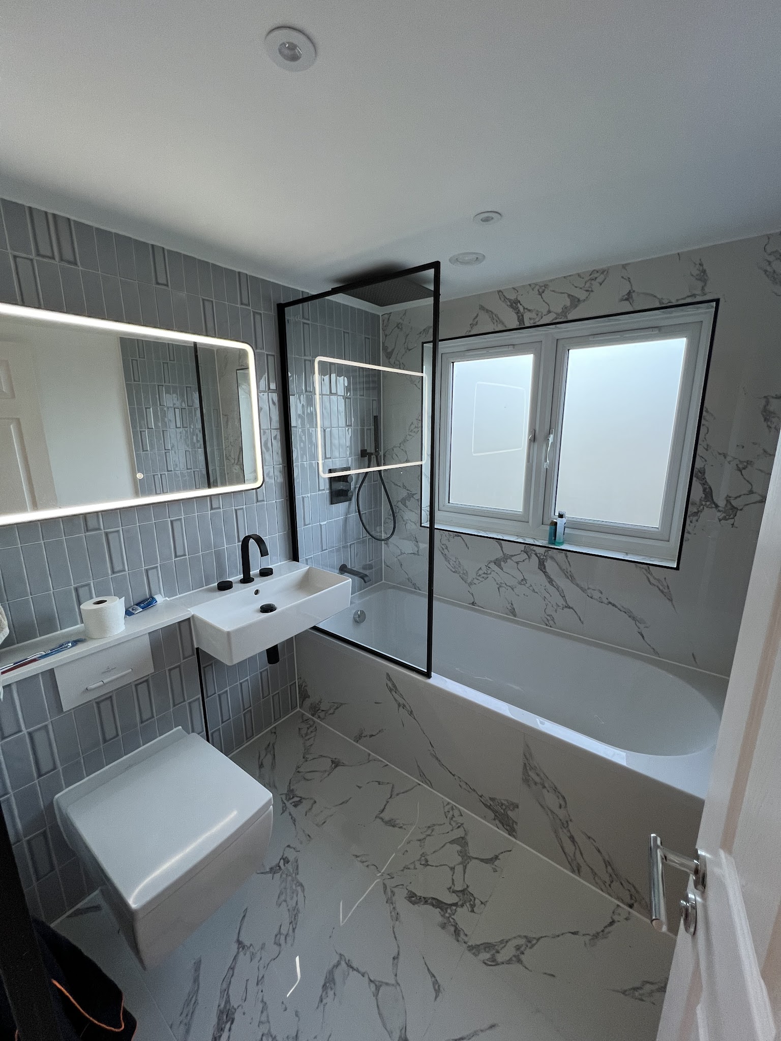 Contemporary grey bathroom with marble-effect tiles and black fixtures