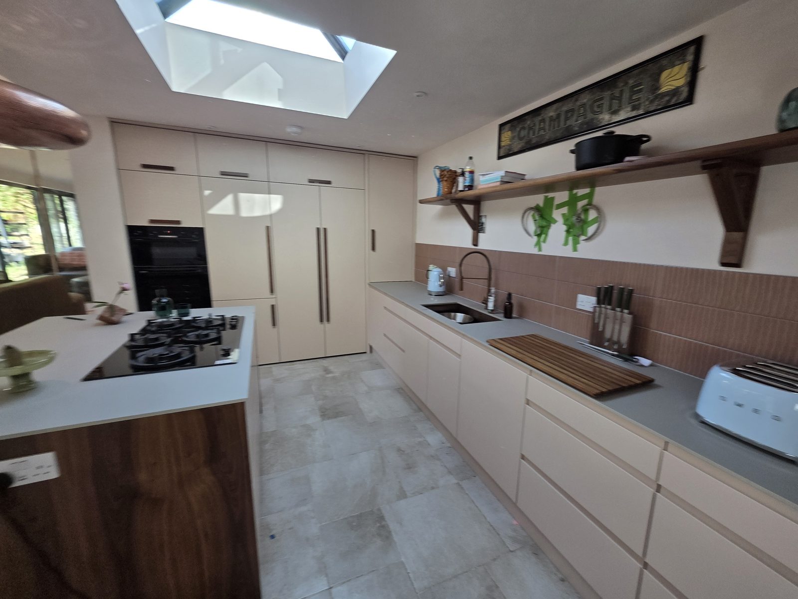 Cream kitchen with a large island, wood worktop and three pendant lights