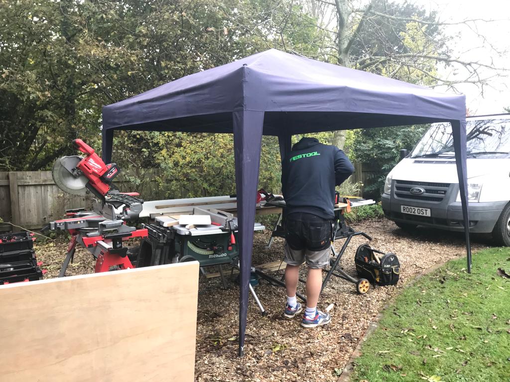 George on site under the gazebo — tools set up, working at the bench